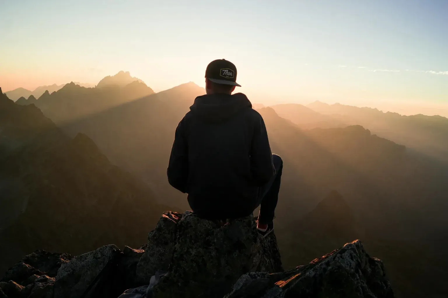 Man standing on a mountain top, looking out