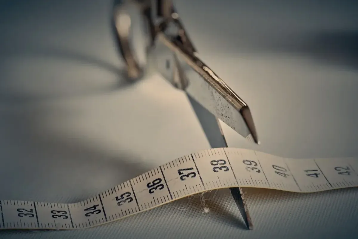 Scissors cutting through a measuring tape
