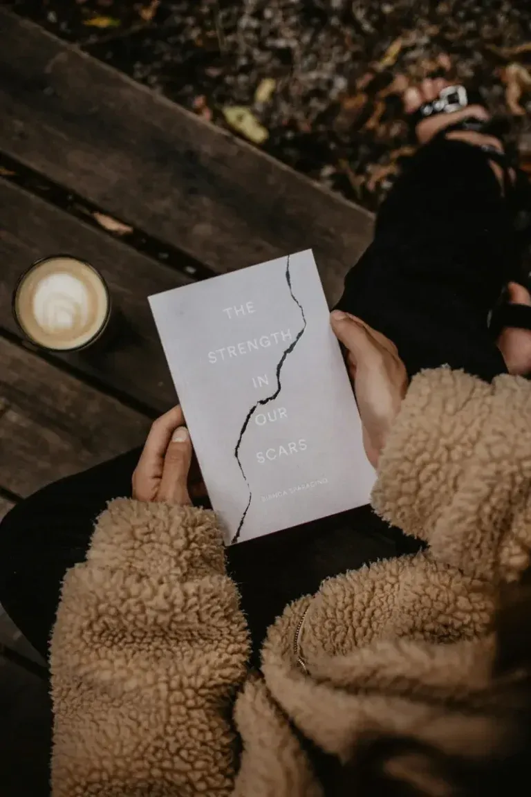 Person reading a book with a coffee on a deck